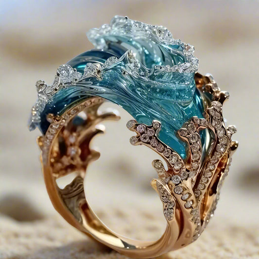 Close-up of a sky blue wave resin ring featuring a gold-tone band with coral-inspired details and sparkling rhinestones, designed to mimic the motion of ocean waves.