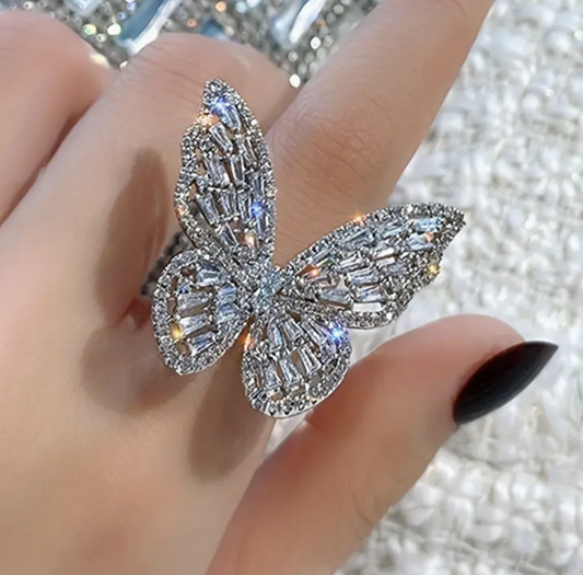 Close-up of a rhinestone butterfly adjustable ring, sparkling with baguette-cut stones on a woman's finger.