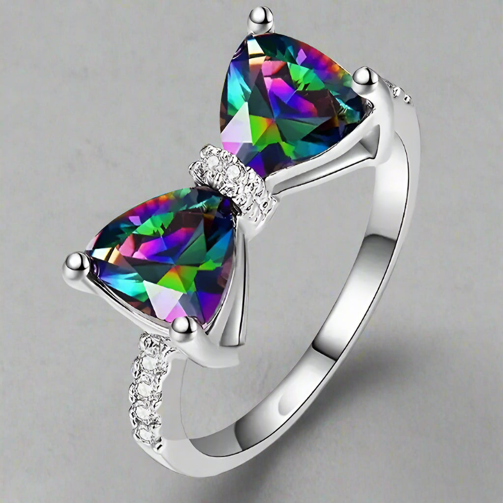 A silver bow-shaped ring featuring two iridescent, multicolored gemstones with sparkling cubic zirconia accents, set on a polished S925 sterling silver band.